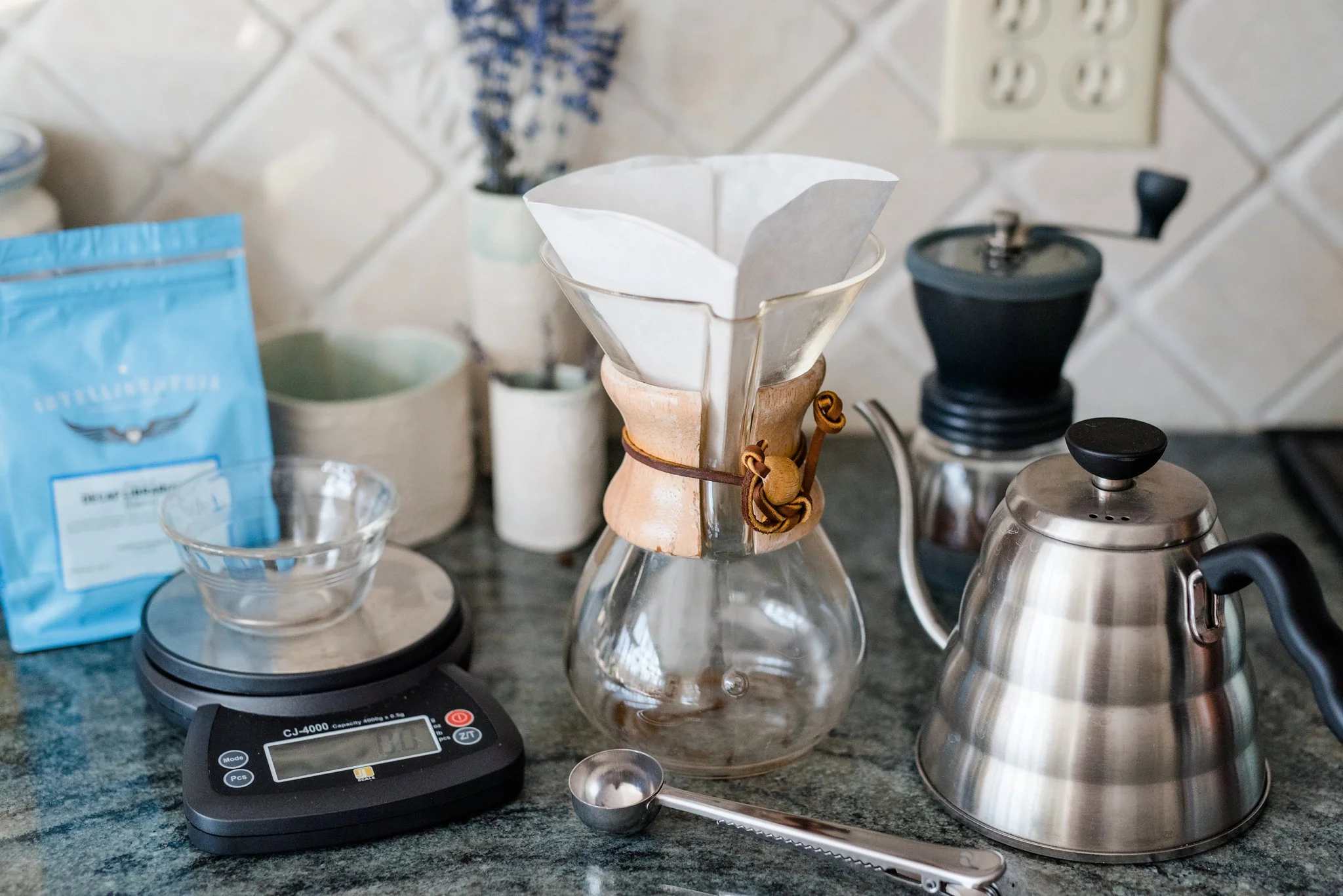 So here is a photo of our arsenal! The scale, the scooper to measure out the beans, the grinder is in the background. We actually have a really fast electric one but I just used this one today because it is easier to photograph (this is a hand one which is a little tough to use for me to use). The kettle on the right is awesome to do pour overs with because you can control the amount of water coming out. You really want to pour nice and slow. The carafe is in the middle and the filter is placed on top.