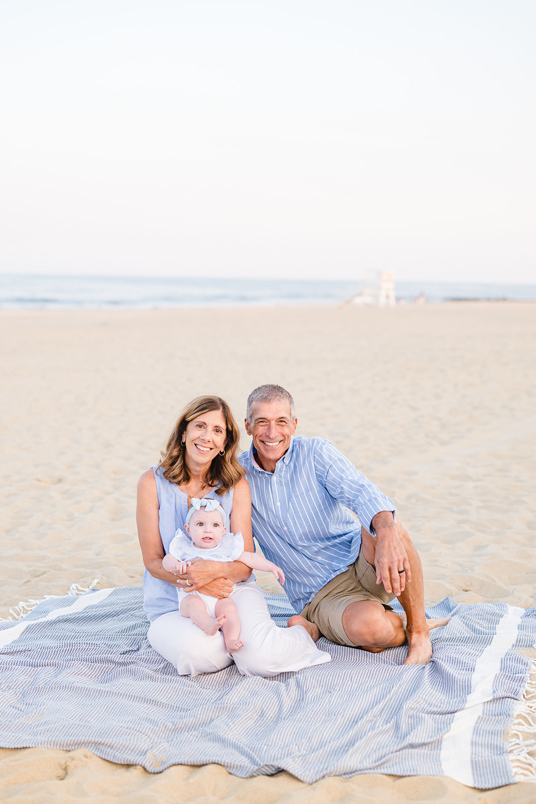 Beach family portrait of parents and grandparents sitting together with their baby during a first year family session