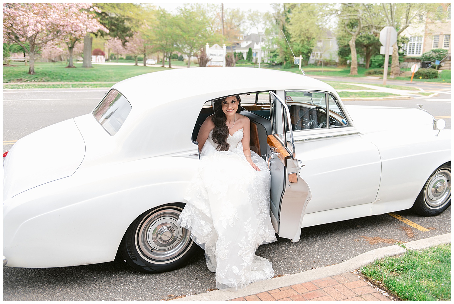pretty bride in her antique car waiting to meet her groom amid the cherry blossoms