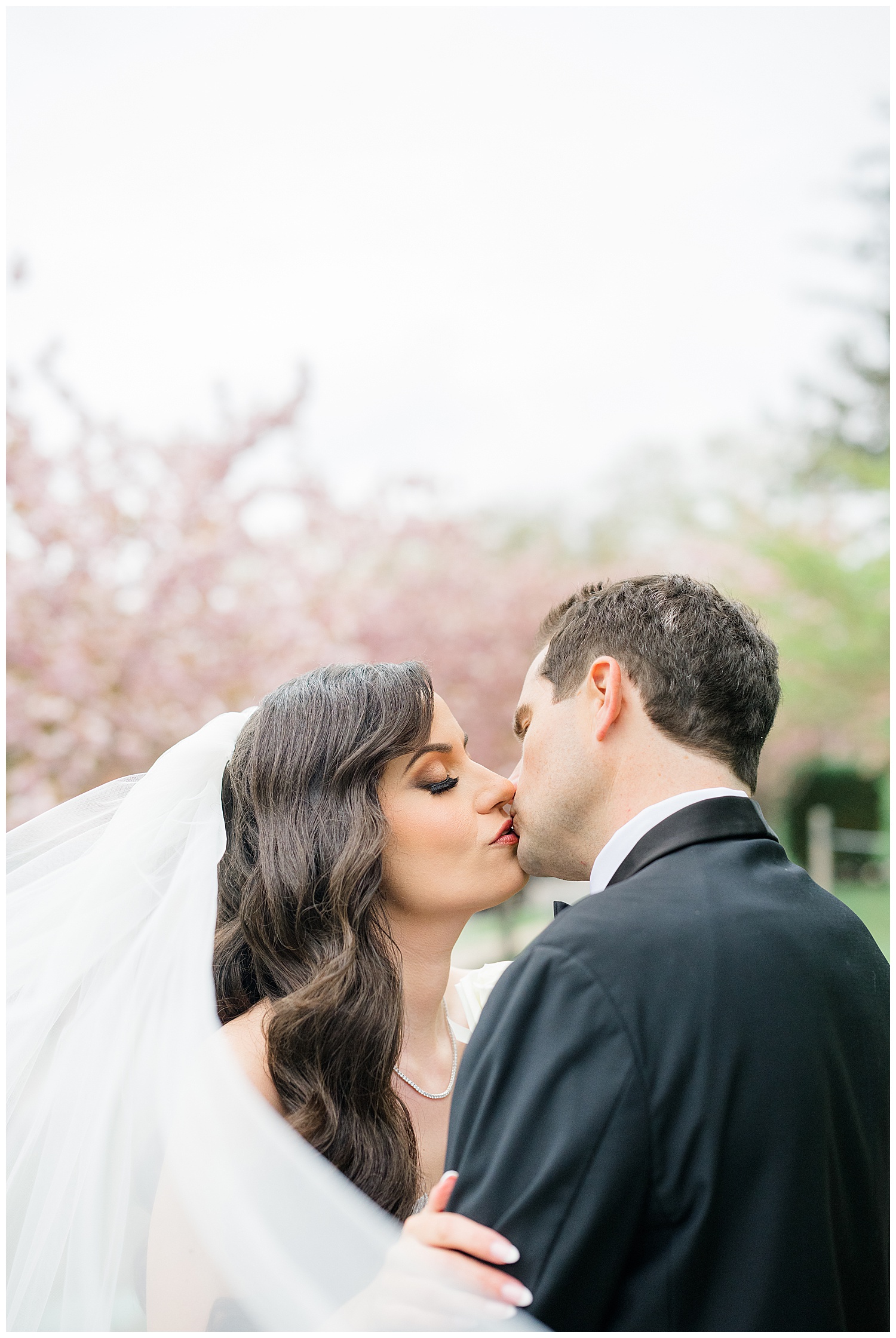 bride and groom kissing among the cherry blossoms