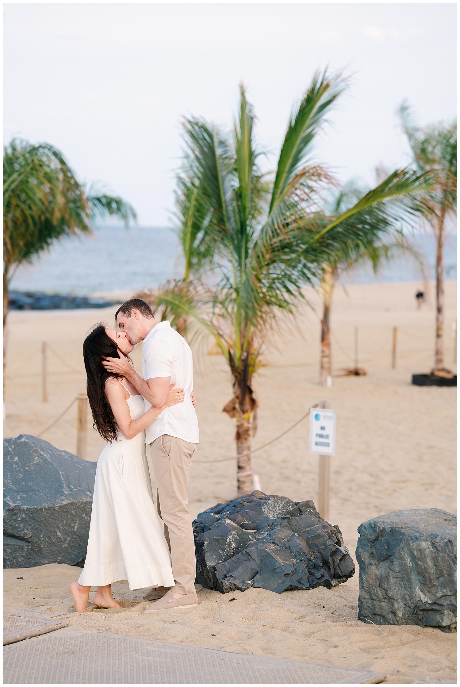 engaged couple kissing under palm tress on a turquoise beach