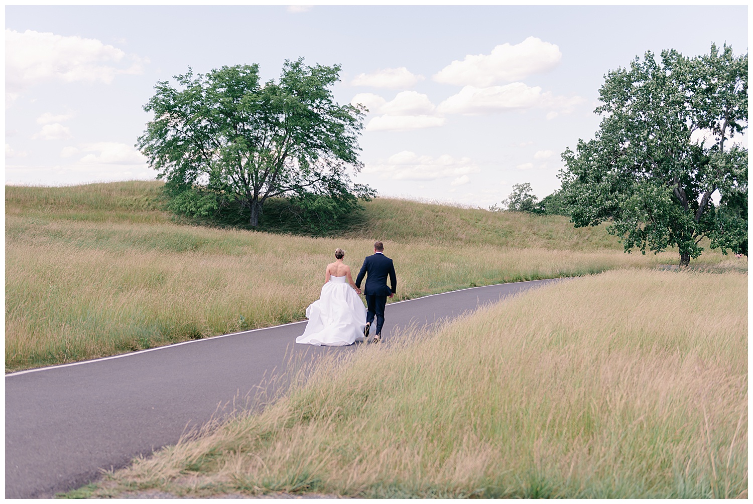 a newly married couple walking in a field on their wedding day