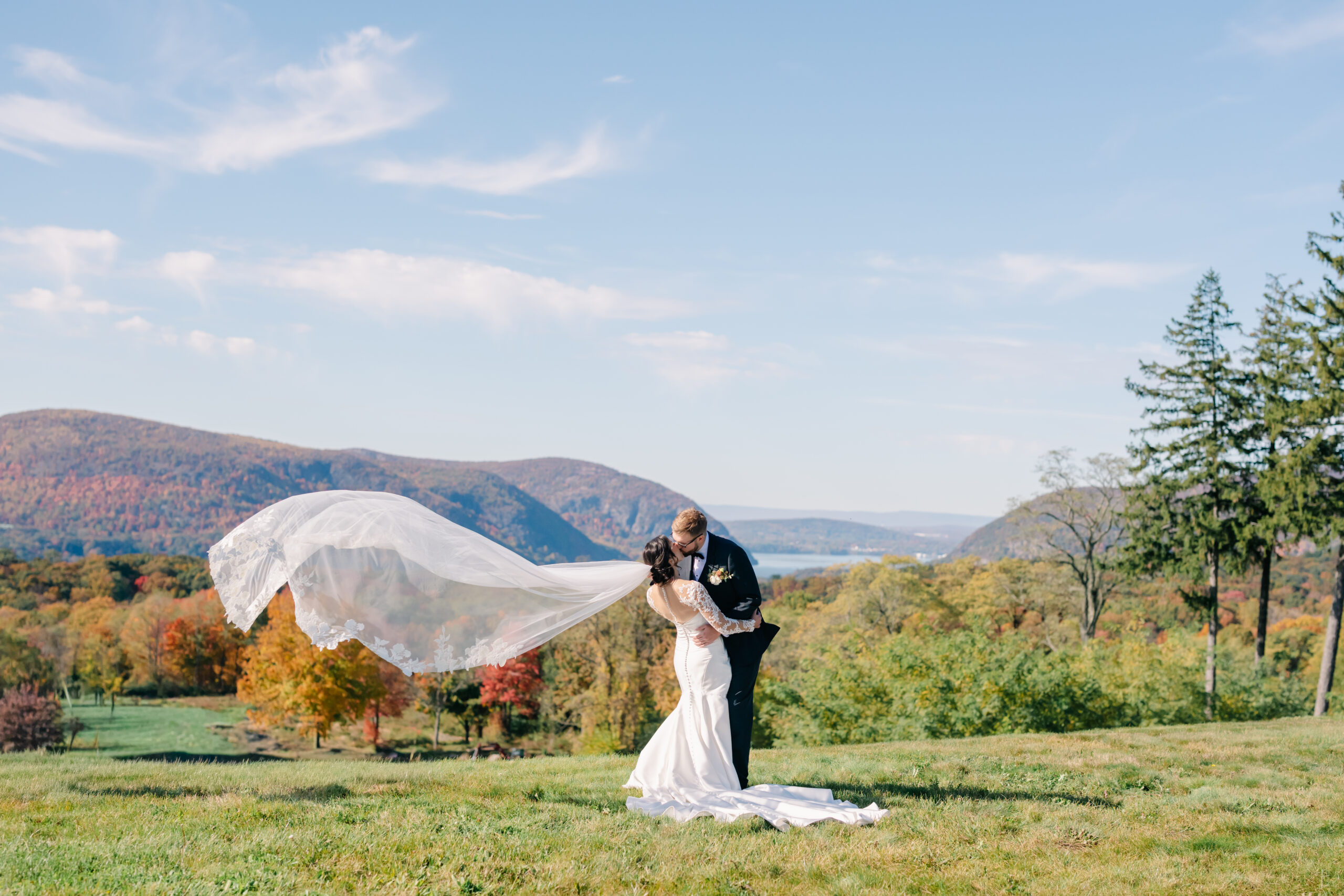 bride and groom kissing with a veil flying on a mountaintop